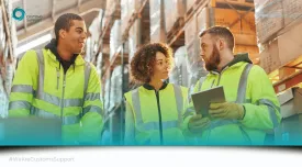 Three people discussing logistics in a warehouse.